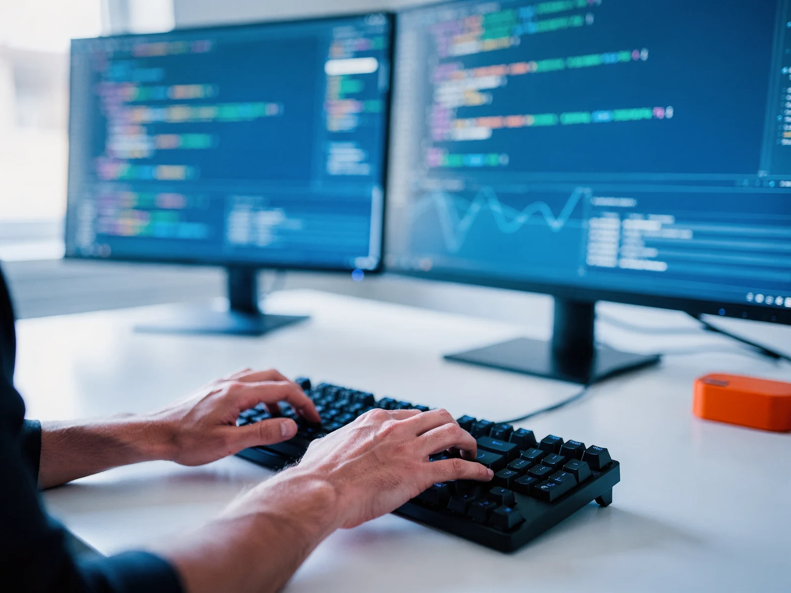 Developer writing code at a dual-monitor workstation